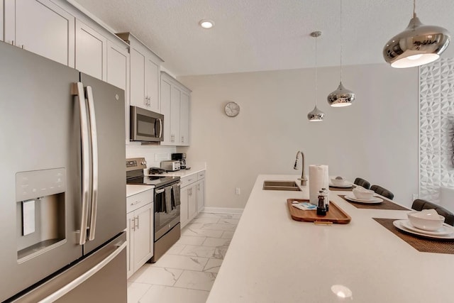 kitchen featuring backsplash, a textured ceiling, stainless steel appliances, sink, and pendant lighting