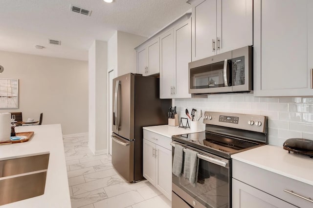 kitchen with backsplash, sink, stainless steel appliances, and a textured ceiling