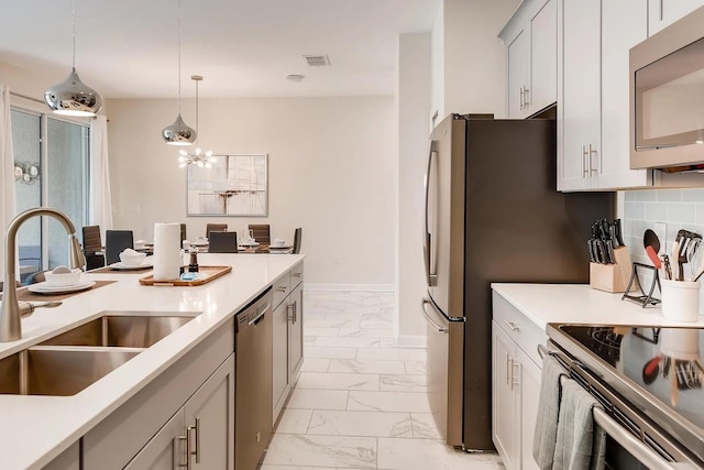 kitchen featuring appliances with stainless steel finishes, backsplash, pendant lighting, and sink