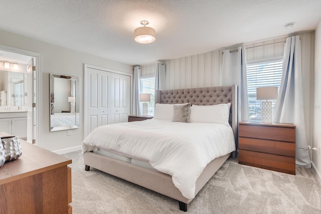 carpeted bedroom featuring connected bathroom, a closet, and a textured ceiling