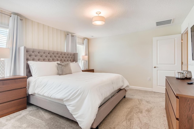 bedroom featuring light carpet and a textured ceiling