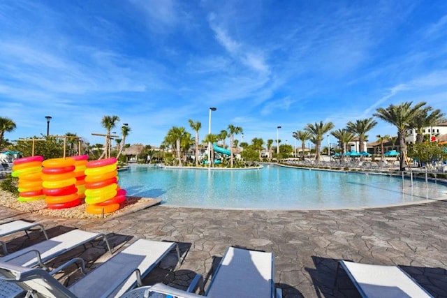 view of swimming pool with a water slide and a patio