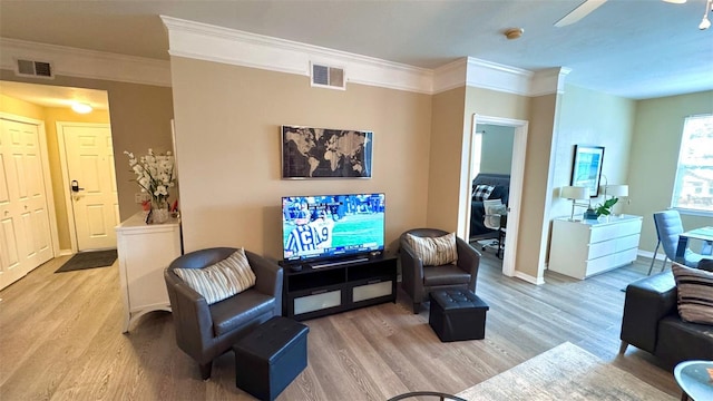 living room with ornamental molding, light wood-type flooring, and ceiling fan