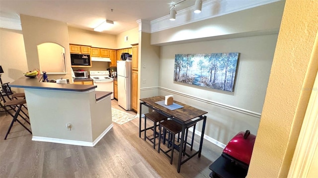 kitchen featuring white appliances, kitchen peninsula, ornamental molding, a kitchen bar, and light hardwood / wood-style floors