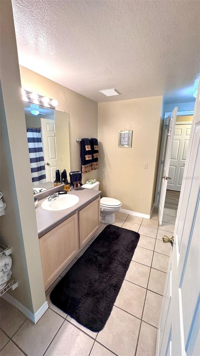 bathroom with vanity, a textured ceiling, toilet, and tile patterned floors