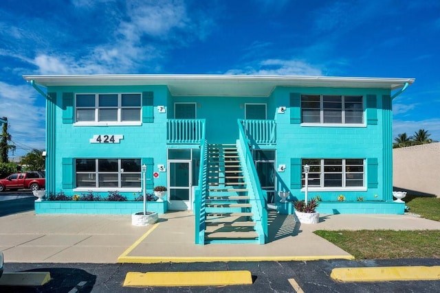 exterior space featuring stairs, concrete block siding, and uncovered parking