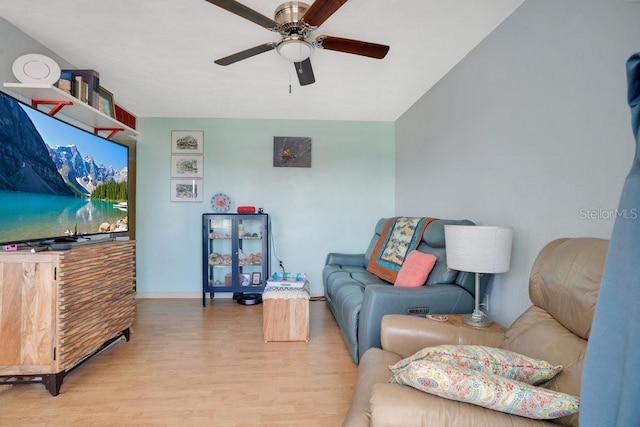 living room with baseboards, a ceiling fan, and light wood-style flooring