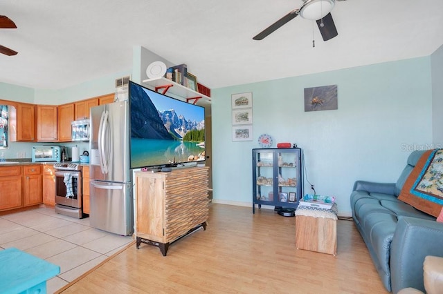 living area featuring baseboards, a ceiling fan, and light wood finished floors