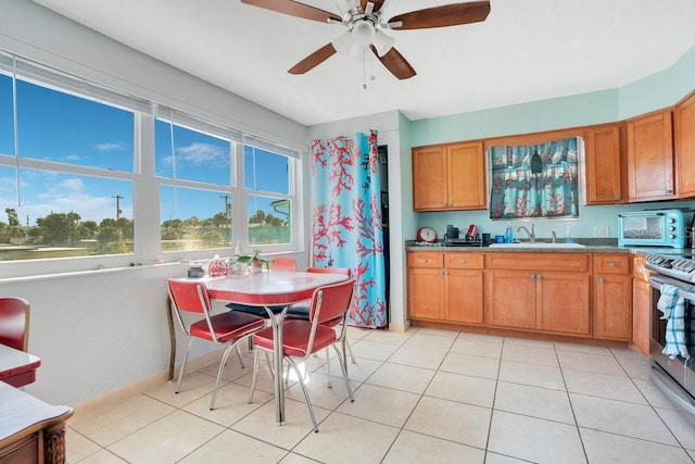 kitchen with sink, stainless steel range with electric cooktop, light tile patterned floors, and ceiling fan