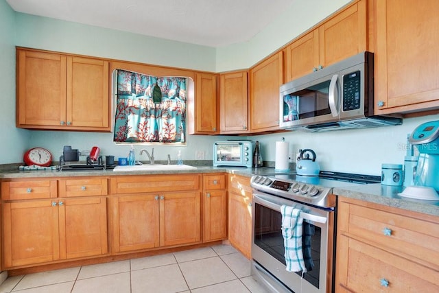 kitchen with a sink, light countertops, a toaster, stainless steel appliances, and light tile patterned flooring