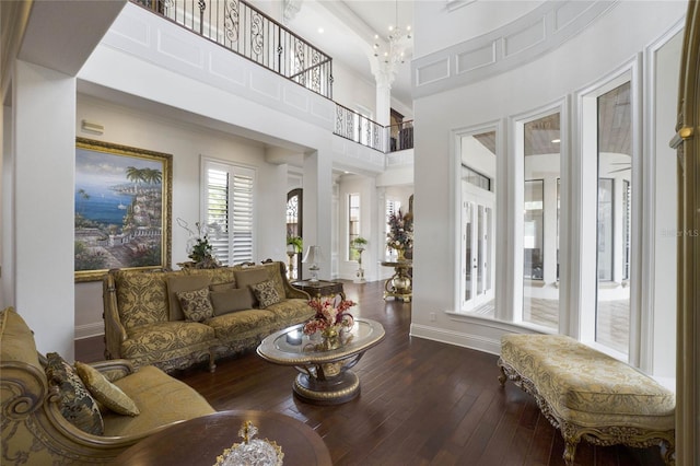 living room with a high ceiling, dark wood-type flooring, and an inviting chandelier