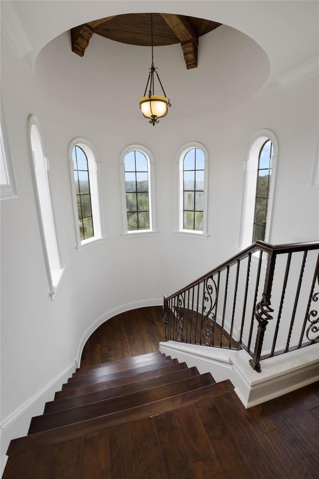 stairway with hardwood / wood-style flooring and beamed ceiling