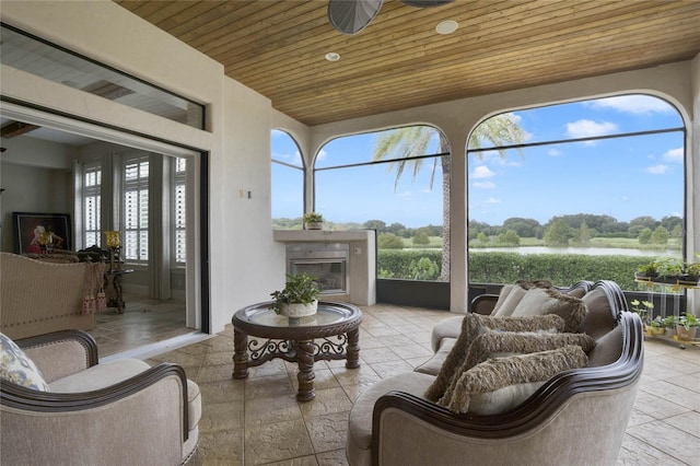 sunroom with a water view, wood ceiling, and ceiling fan