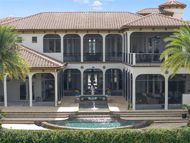 rear view of property with french doors, a balcony, and a patio area