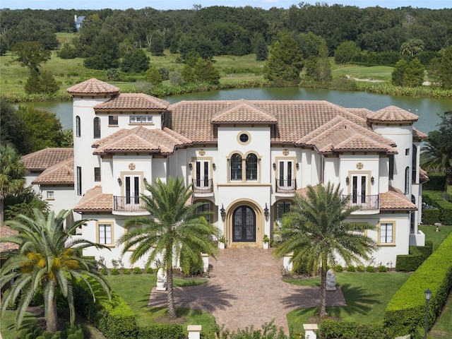 mediterranean / spanish-style house featuring a front yard, a balcony, and a water view