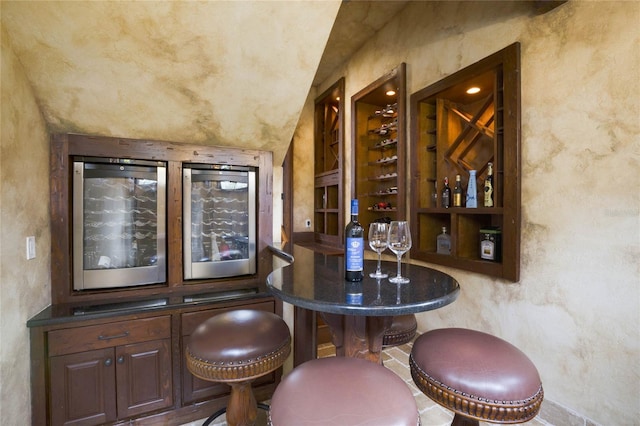 wine cellar with lofted ceiling and bar area