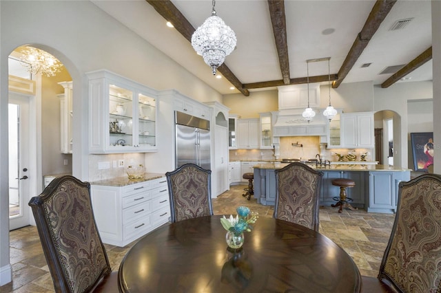 dining space with sink, a chandelier, beam ceiling, and a wealth of natural light