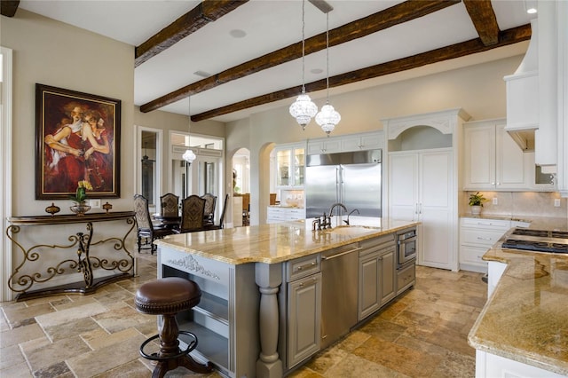 kitchen featuring light stone counters, white cabinets, an island with sink, gray cabinetry, and stainless steel appliances