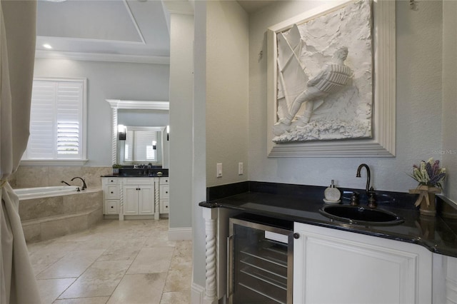 bar with white cabinets, beverage cooler, and sink