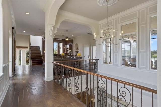 corridor with decorative columns, dark hardwood / wood-style floors, ornamental molding, and a wealth of natural light