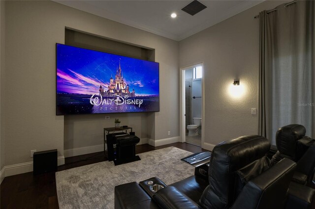 cinema room with ornamental molding and dark hardwood / wood-style flooring