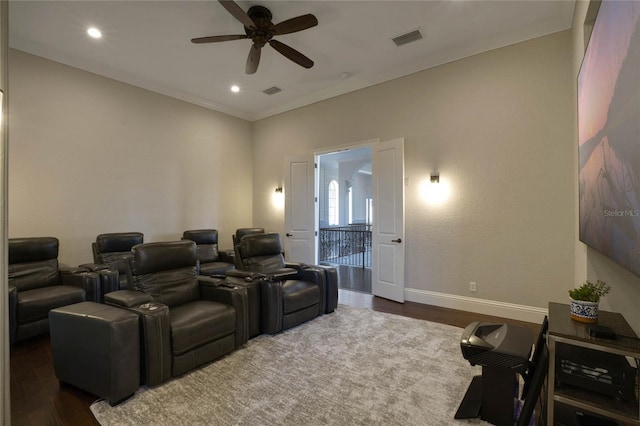 cinema room featuring dark wood-type flooring, ornamental molding, and ceiling fan