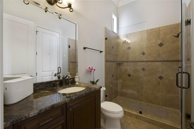 bathroom featuring a shower with door, vanity, and toilet