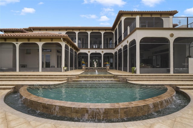 rear view of house featuring a balcony, a patio, a sunroom, and pool water feature