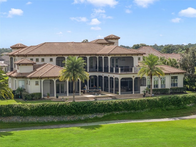 back of property with a lawn, a balcony, and a patio area