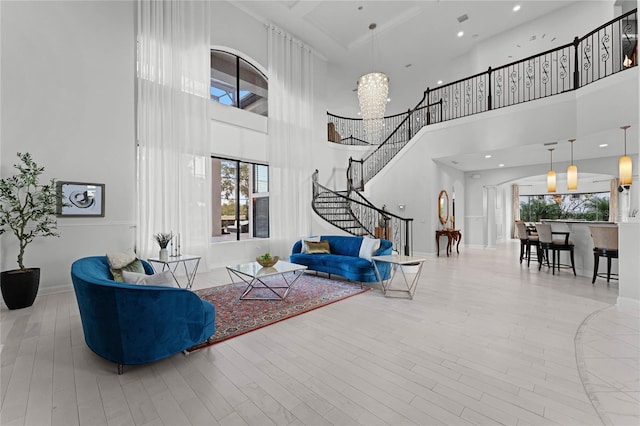 living room featuring light hardwood / wood-style flooring, a notable chandelier, and a high ceiling