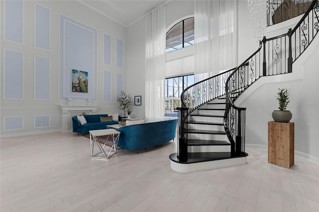 staircase with ornamental molding, wood-type flooring, and a towering ceiling