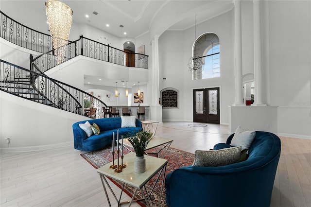 living room with french doors, a towering ceiling, wood-type flooring, and an inviting chandelier