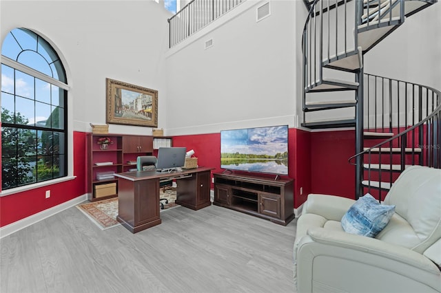 office space with light hardwood / wood-style flooring and a towering ceiling