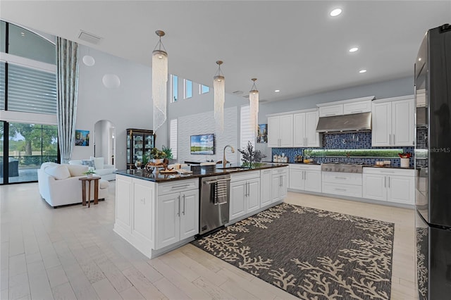 kitchen with ventilation hood, white cabinets, stainless steel appliances, and a high ceiling