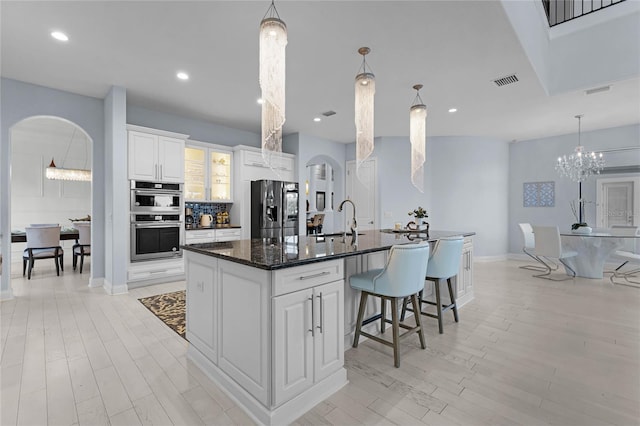 kitchen featuring white cabinetry, stainless steel appliances, light hardwood / wood-style floors, and an island with sink