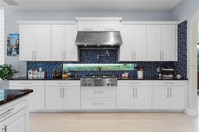 kitchen featuring wall chimney exhaust hood, white cabinetry, stainless steel gas cooktop, and tasteful backsplash