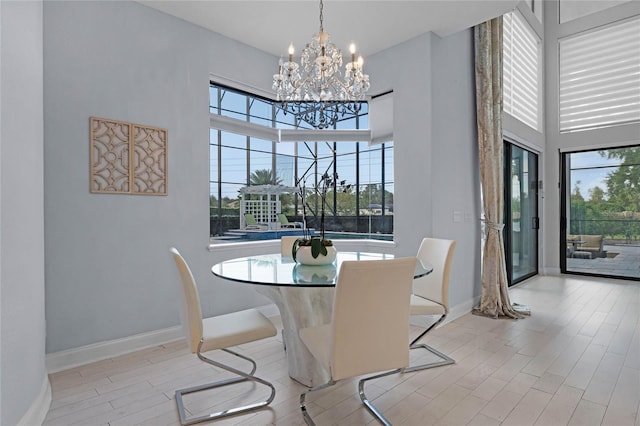 dining space with a high ceiling, a notable chandelier, and light wood-type flooring