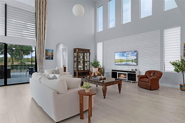 living room featuring light wood-type flooring and a towering ceiling