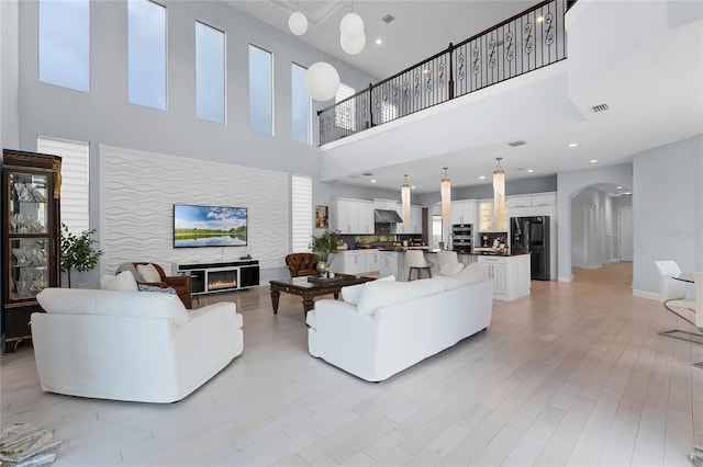 living room with a towering ceiling and light hardwood / wood-style flooring