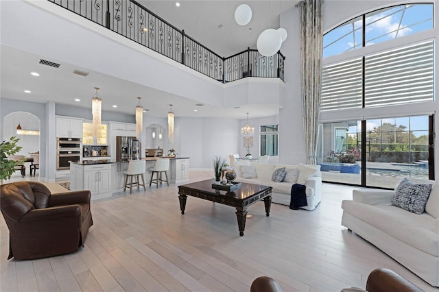 living room featuring a notable chandelier, a high ceiling, and light wood-type flooring