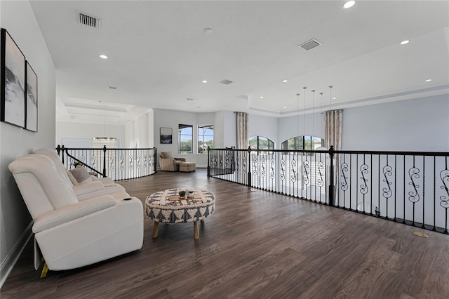 sitting room featuring dark wood-type flooring, a chandelier, and a raised ceiling