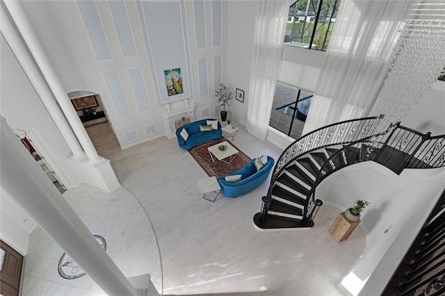 living room with light hardwood / wood-style floors, ornate columns, and a towering ceiling