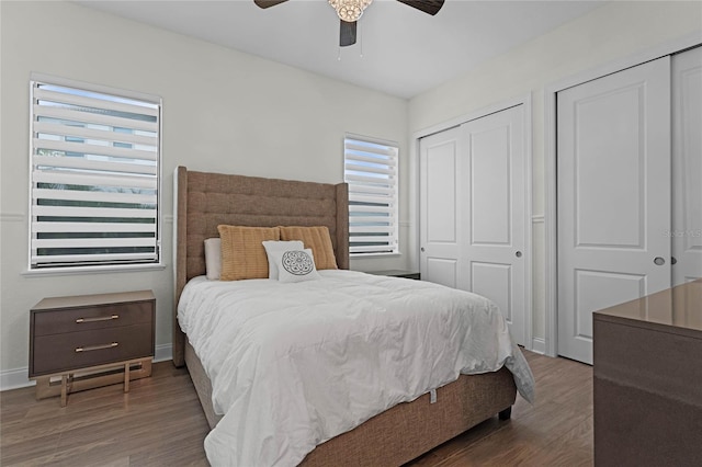 bedroom featuring ceiling fan, two closets, and dark hardwood / wood-style flooring