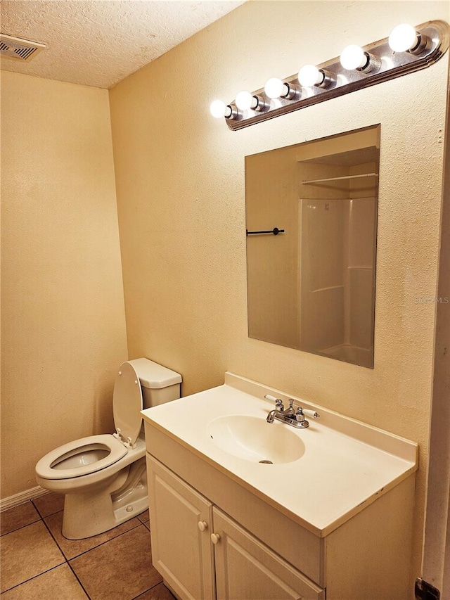 bathroom with vanity, a textured ceiling, walk in shower, tile patterned flooring, and toilet