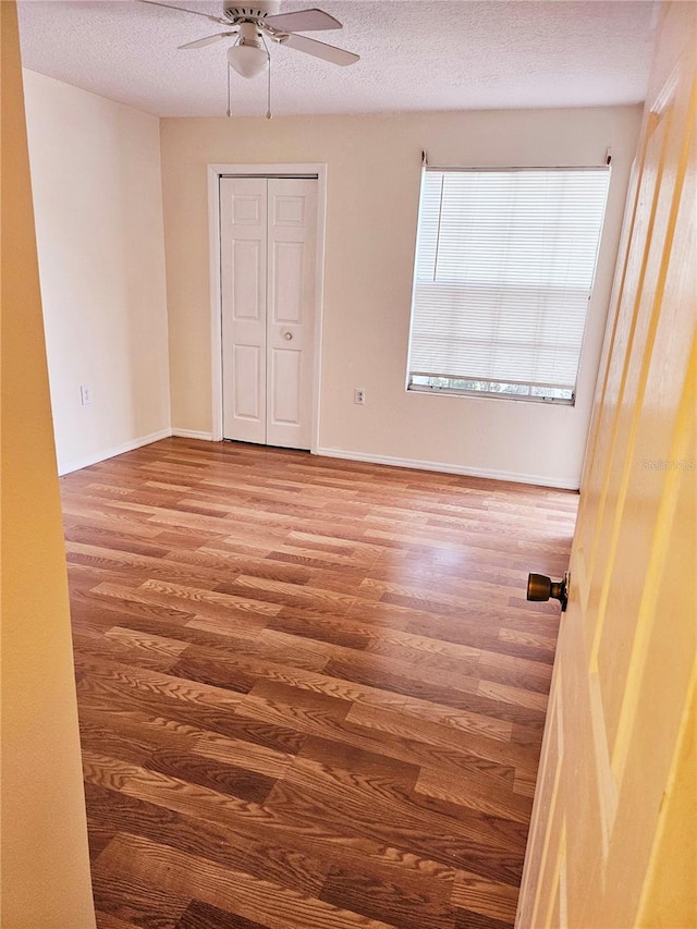 empty room with ceiling fan, hardwood / wood-style flooring, and a textured ceiling