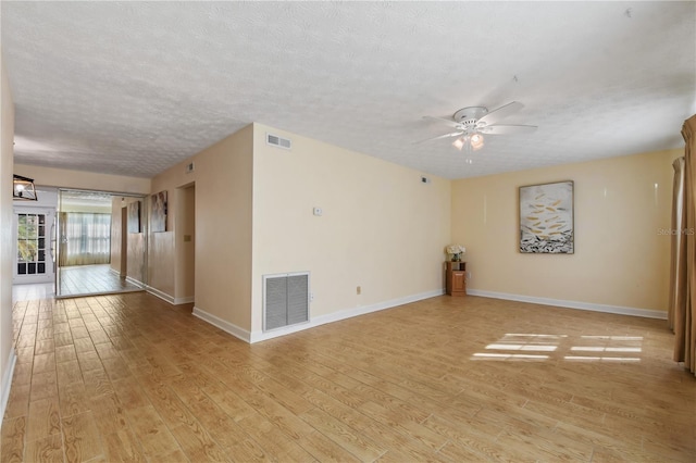 empty room featuring a textured ceiling, light wood-type flooring, and ceiling fan