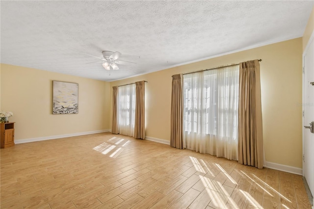 spare room featuring baseboards, light wood finished floors, ceiling fan, and a textured ceiling