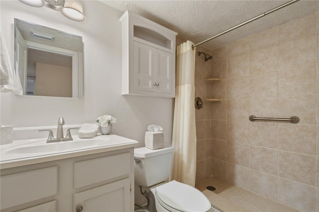 bathroom with a textured ceiling, toilet, vanity, and tiled shower