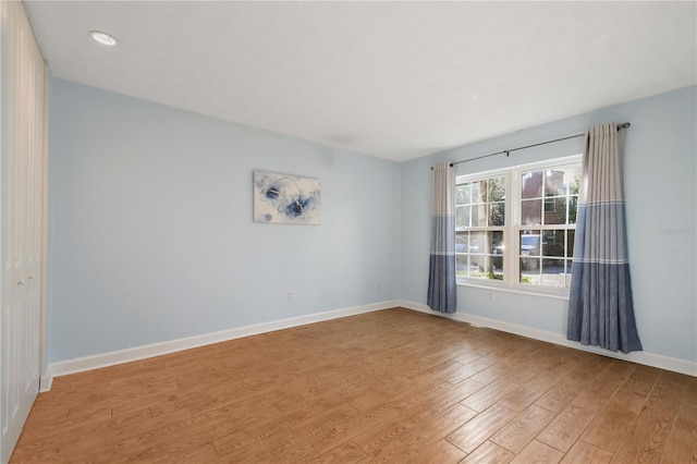 empty room with baseboards, recessed lighting, and wood finished floors