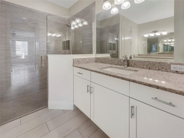 bathroom featuring tile patterned flooring, a shower with door, and vanity